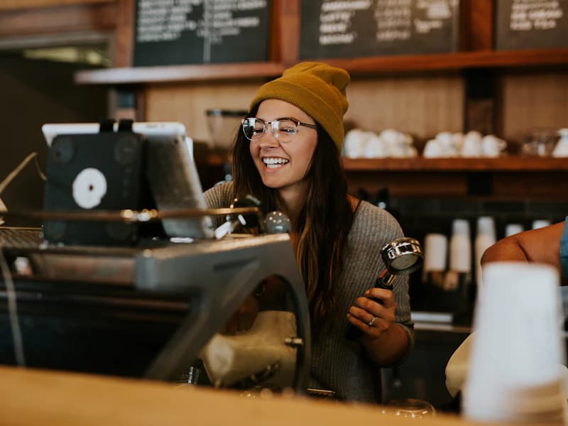 A smiling young person in a work apron